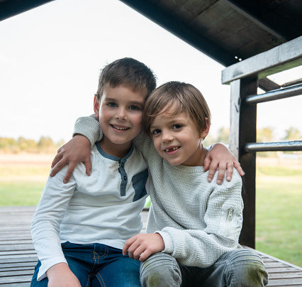 Close-up  Portrait of Two smiling boys, brothers sitting outdoor and looking at camera