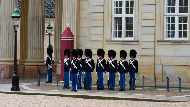 soldados de infantaria da guarda real da dinamarca (den kongelige livgarde) aguardando a troca de guardas no castelo histórico de amalienborg. - changing the guard - fotografias e filmes do acervo