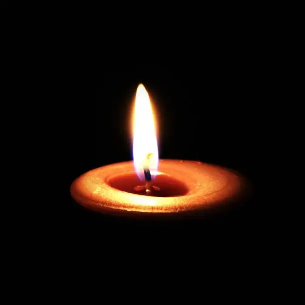 This candle flame is still and peaceful within the surrounding darkness.