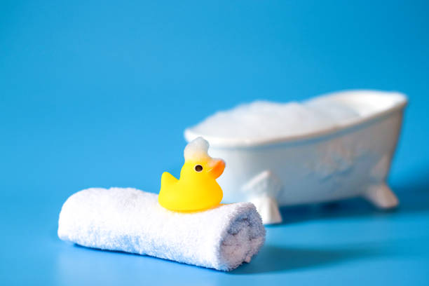 istock yellow rubber duck for bathing with foam on a towel on a blue background with a bath 1281831083