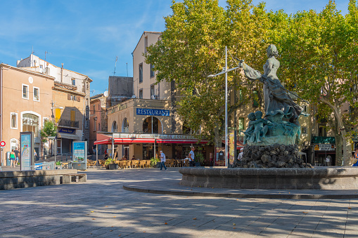 Agde, France, July 19th, 2020 : Agde Centre with old Buildings and a sculpture in the fountain, street view of the town