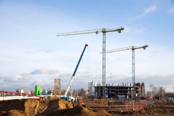 istock Hydraulic luffing jib tower cranes and workers being poured concrete into foundation. Cement pouring into formwork of building at construction site. Tower cranes constructing a new residential build 1281833813
