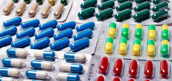 Pharmaceuticals, antibiotics, tablets, medications. Colorful antibacterial pills on a dark background. Capsules, tablets, medications