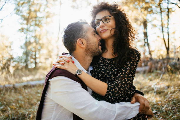 Handsome mid adult couple enjoying outdoors in the woods or park. Bright sunny day and autumn foliage.