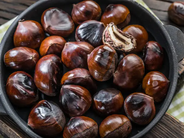 Photo of Roasted edible chestnut fruits in the pan. Top view.