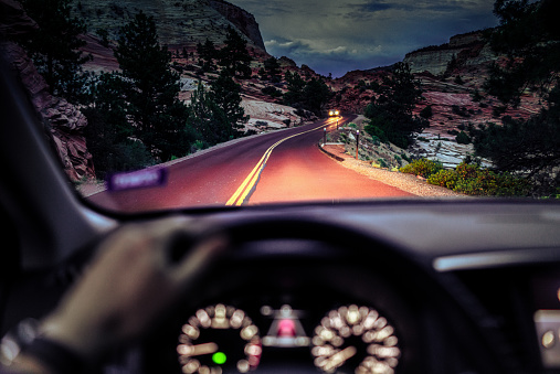 A driver's point of view on a country journey on a winding road in southern Utah, as a car approaches.