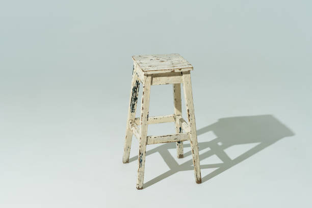 istock Tall retro stool or tabouret with peeling white paint on white background. Empty place 1281842441