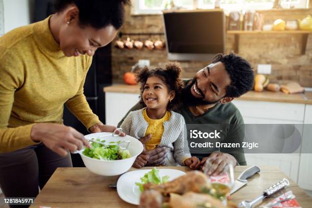 Feliz Chica Afroamericana Almorzando El Día De Acción De Gracias Con Sus Padres En La Mesa De Comedor Foto de stock y más banco de imágenes de Familia