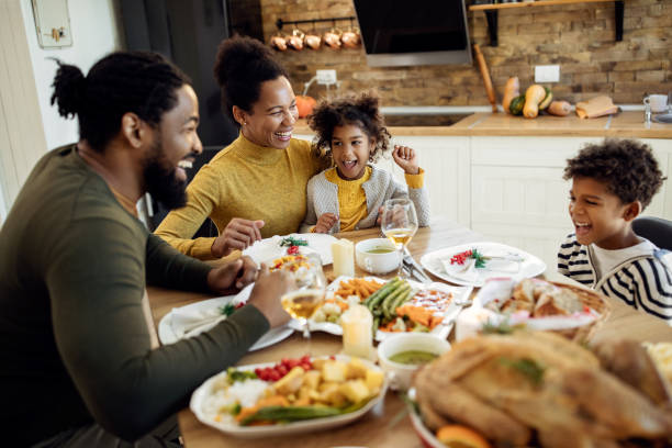 istock Cheerful black family having fun during Thanksgiving meal at dining table. 1281846904