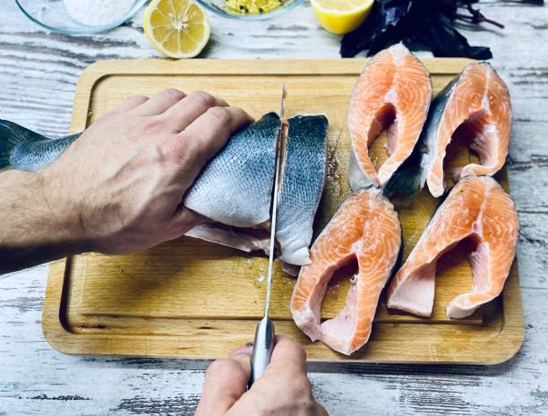 istock A fair-skinned man cuts raw fish for cooking. 1281846944