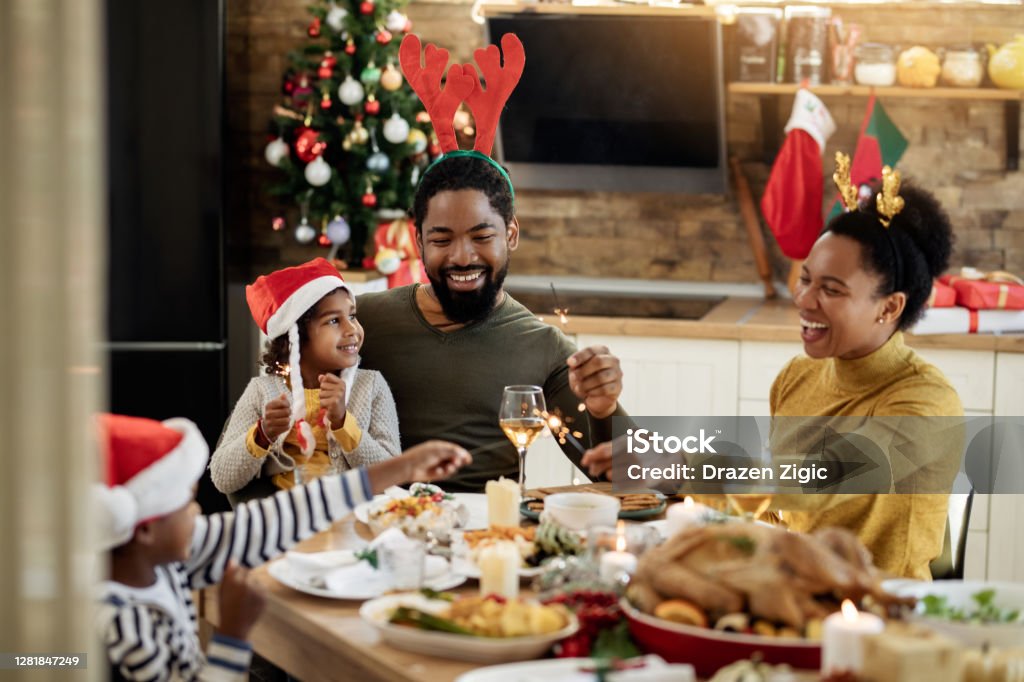 Happy black family having fun with sparklers during Christmas lunch in dining room. - Royalty-free Natal Foto de stock