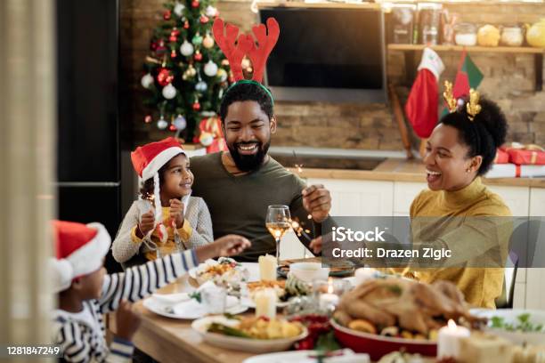 Happy Black Family Having Fun With Sparklers During Christmas Lunch In Dining Room - Fotografias de stock e mais imagens de Natal