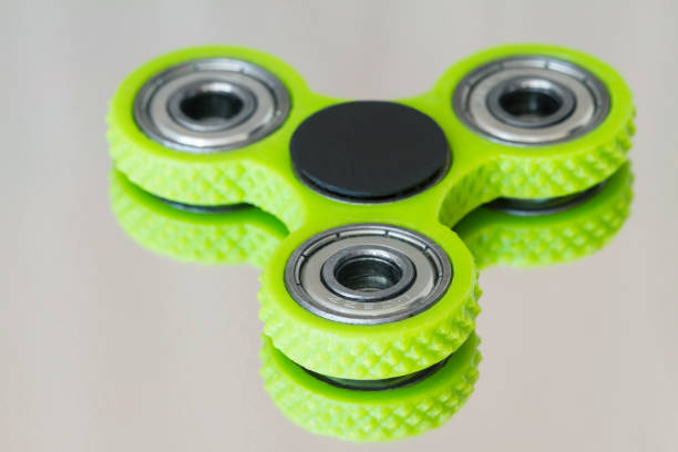 istock A green hand spinner or fidget spinner on light mirror surface. A toy for stress relieving. Close up. Selective focus. 1281850484