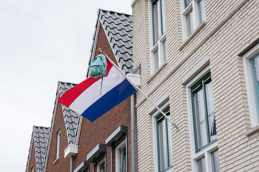Backpack hangs from the Dutch national tricolor\nflag. Tradition in the Netherlands when students have passed their exams.