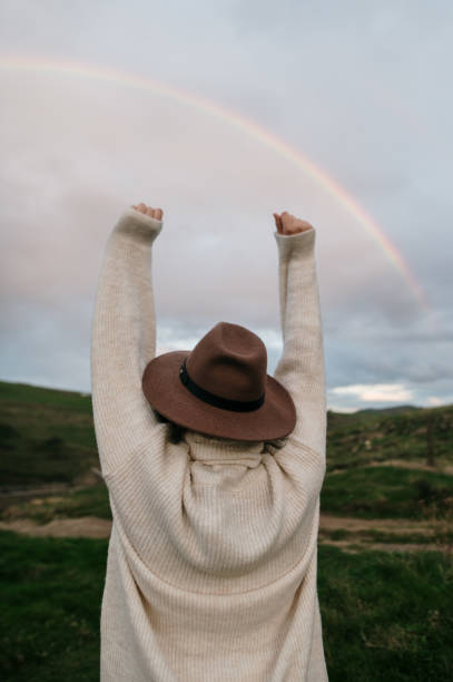 istock Young woman with arms raised by a beautiful rainbow 1281855926