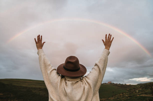 istock Young woman with arms raised by a beautiful rainbow 1281856090