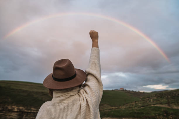 istock Woman with high fist by a rainbow 1281856112