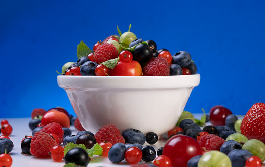 Mix of wild berries on blue background, collection of strawberry, blueberry, raspberry and blackberry