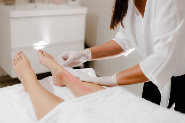 beautician waxing a woman's leg - leg waxing fotografías e imágenes de stock