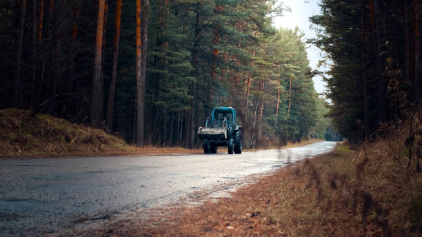 istock The tractor is driving along the road in autumn. Front view 1281857093