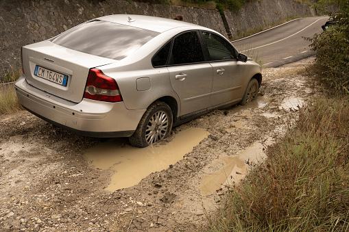 Abruzzo, Italy - July 18, 2020, Silver car stuck deep in mud in Abruzzo, Italy