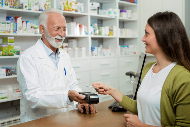 istock Happy senior pharmacist holding credit card reader while looking at customer 1281859970