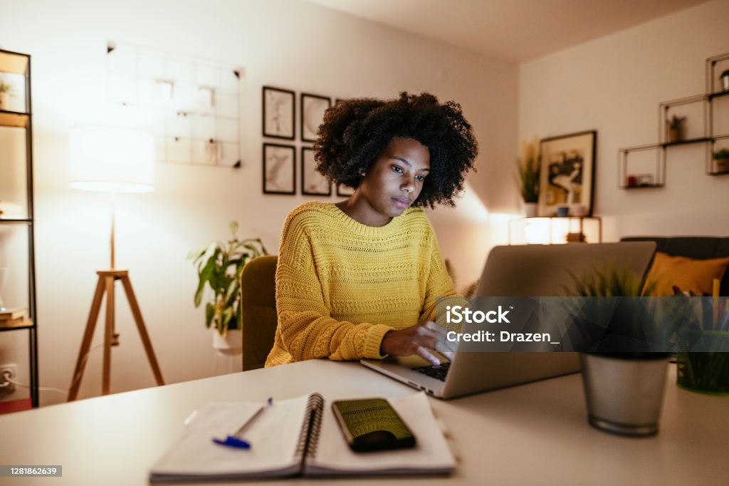 Young African American businesswoman at home office, working late Young African American woman at home, dressed in casual sweater and working or studying. Women Stock Photo