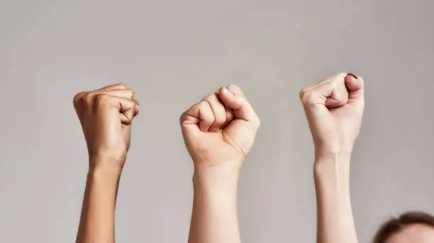 Photo of Close up of three raised fists of diverse women. Feminism, equality and women liberation concept