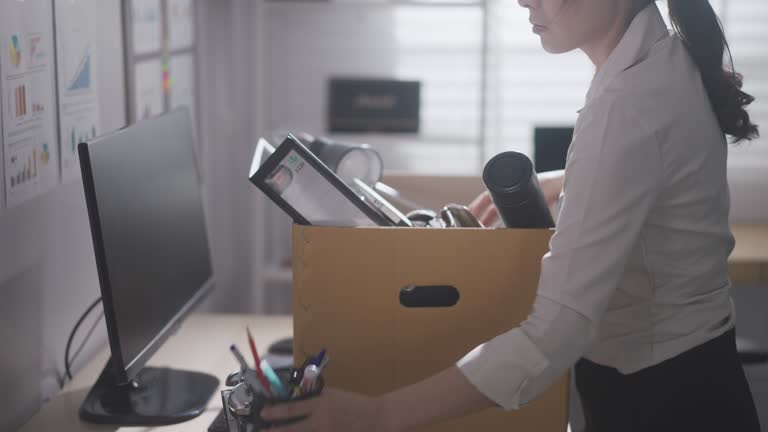 Businesswoman packing her belongings and leaving the office after being fired, employment and crisis concept stock