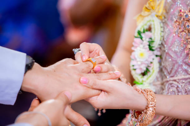 istock Wedding rings. Her Put the Wedding Ring on He. Close up  Bride Put the Ring on Groom. thai wedding ceremony and thai wedding decoration.  Bride Put the Ring on Groom's finger. 1281868967