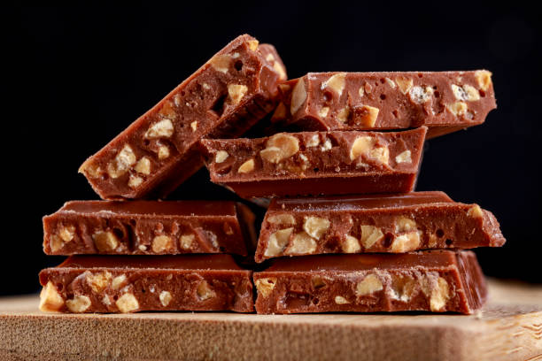 istock Chocolate cubes with nuts on a kitchen board. Tasty dessert prepared to be served. Dark background 1281869967