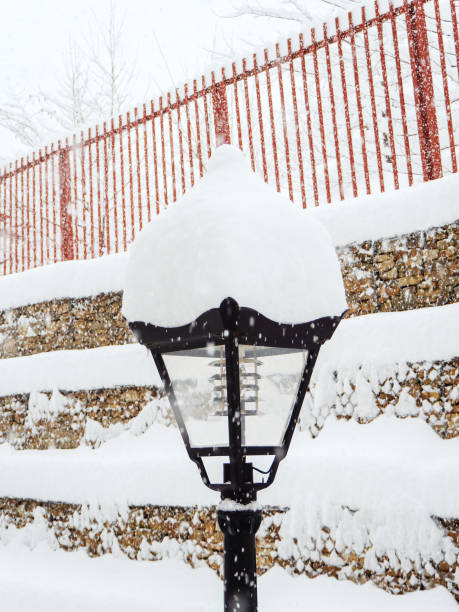 istock Lantern covered with snow on the background of a fence during a snowfall 1281872303