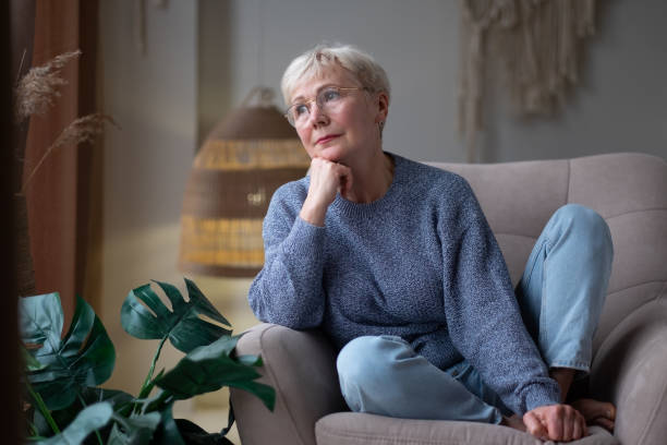istock Grandmother looking in a window sitting at home alone, dreaming. 1281873261