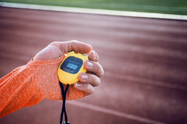 nahaufnahme einer laufenden stoppuhr in der hand eines jungen sportlers - starting line running sprinting alertness stock-fotos und bilder