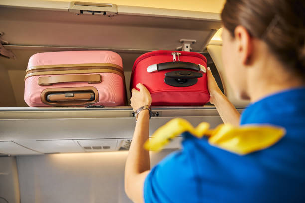 istock Stewardess putting a suitcase into an overhead compartment 1281875471
