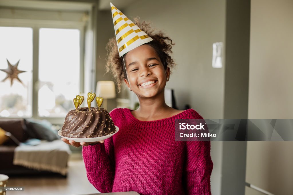 Portrait of African American girl with birthday cake at home African American girl holding a birthday cake and smiling Birthday Stock Photo