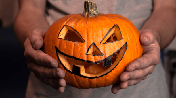 istock A young man, holds out a halloween pumpkin or jack-o-lantern . The young master made a jack-o-lantern for the Halloween party. 1281877967