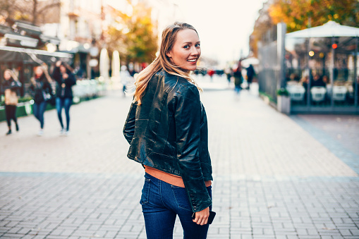 Beautiful smiling young woman walking on the street.