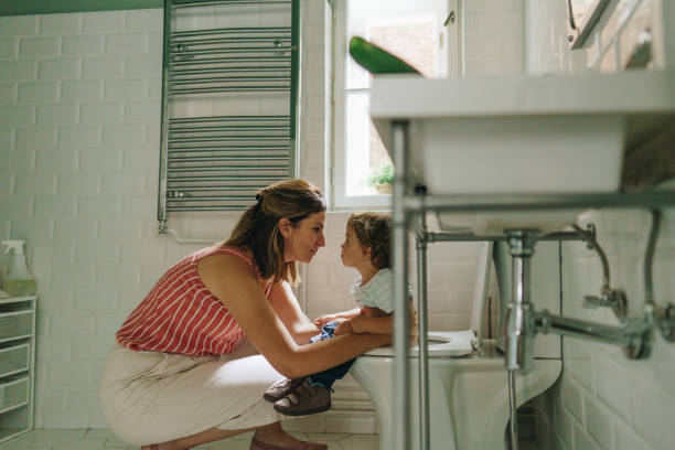 Potty training in progress Photo of a little boy learning to use toilet amenities with a little help from his mother potty toilet child bathroom stock pictures, royalty-free photos & images