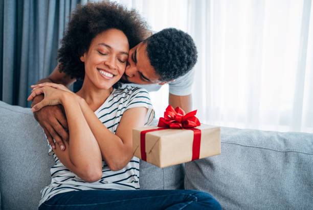 cheerful young woman receiving a gift from her boyfriend. - anniversary present imagens e fotografias de stock