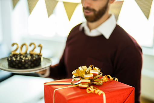 Close up of one man having a fun, holding chocolate cake and Christmas present