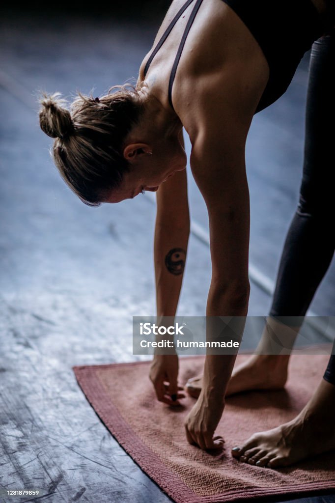 Side view of a beautiful fit young woman and her daily yoga routine Side view of a handsome young Caucasian woman stretching in the empty gym, warming up her muscles and exercising yoga class Yoga Stock Photo