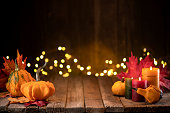 Thanksgiving decoration with pumpkins and greeting card on illuminated background and a rustic wooden table