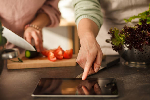 istock Woman following a recipe on digital tablet while preparing food 1281899655