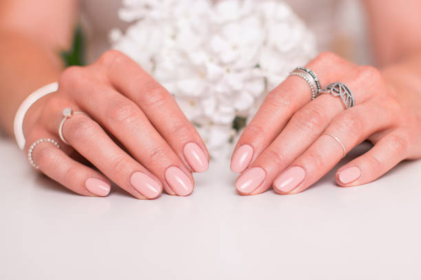 Female hands with wedding manicure nails Beautiful female hands with wedding manicure nails, nude gel polish and white flowers nude coloured stock pictures, royalty-free photos & images