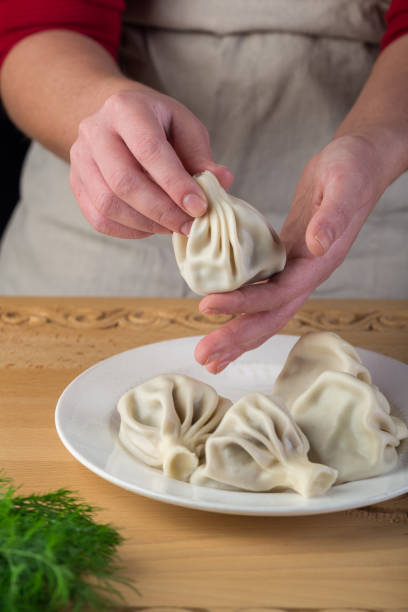 istock Khinkali, Georgian dumplings. Man holding a khinkali in his hand 1281906445