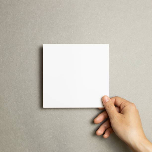 istock Hand holding a blank memo pad, empty paper on gray background. top view, copy space 1281915194