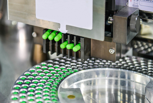 istock Green capsule medicine pill production line, Industrial pharmaceutical concept. 1281923833