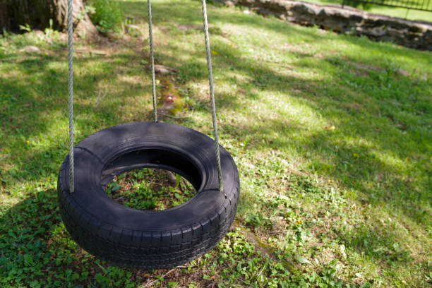 одинокие качели шин ждет в солнечном д�воре - tire swing стоковые фото и изображения