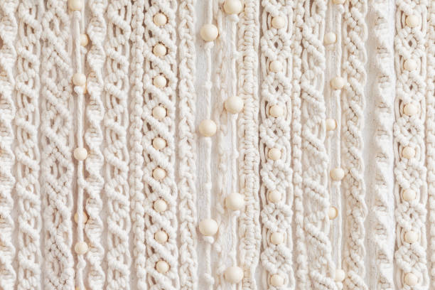 Close-up of hand made macrame texture pattern. Eco friendly modern knitting. Natural decoration concept in the interior. Handmade macrame wall hanging 100% cotton and wooden beads stock photo